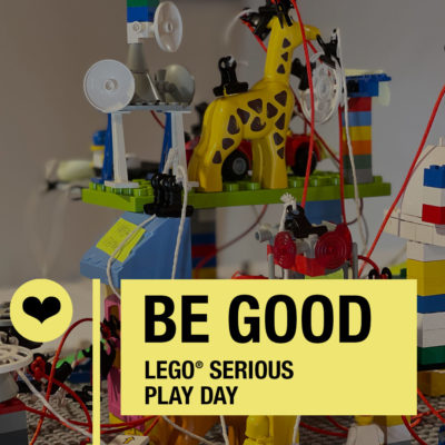 Colorful LEGO creation with a giraffe, featuring text about a LEGO Serious Play Day event.