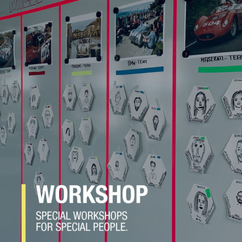 Interaktive Wand mit Teambildern und Schildern für spezielle Workshops, die kreative Zusammenarbeit fördern.