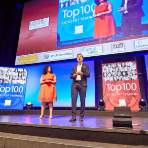 Due relatori sul palco annunciano i vincitori del premio Top 100 per formatori ed oratori eccellenti.