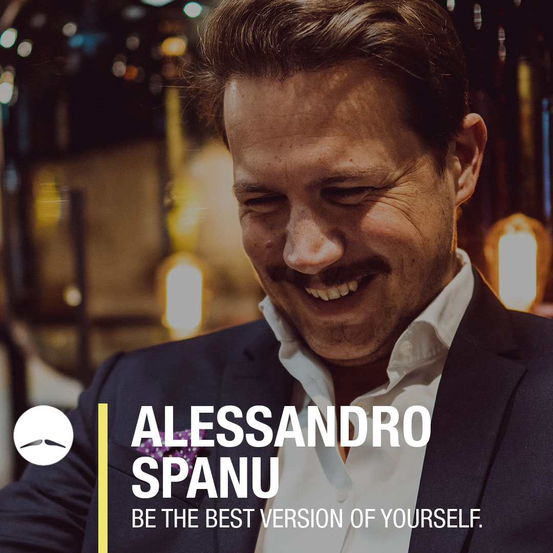 Alessandro Spanu lächelt selbstbewusst in einem eleganten Anzug und inspiriert zur besten Version seiner selbst.
