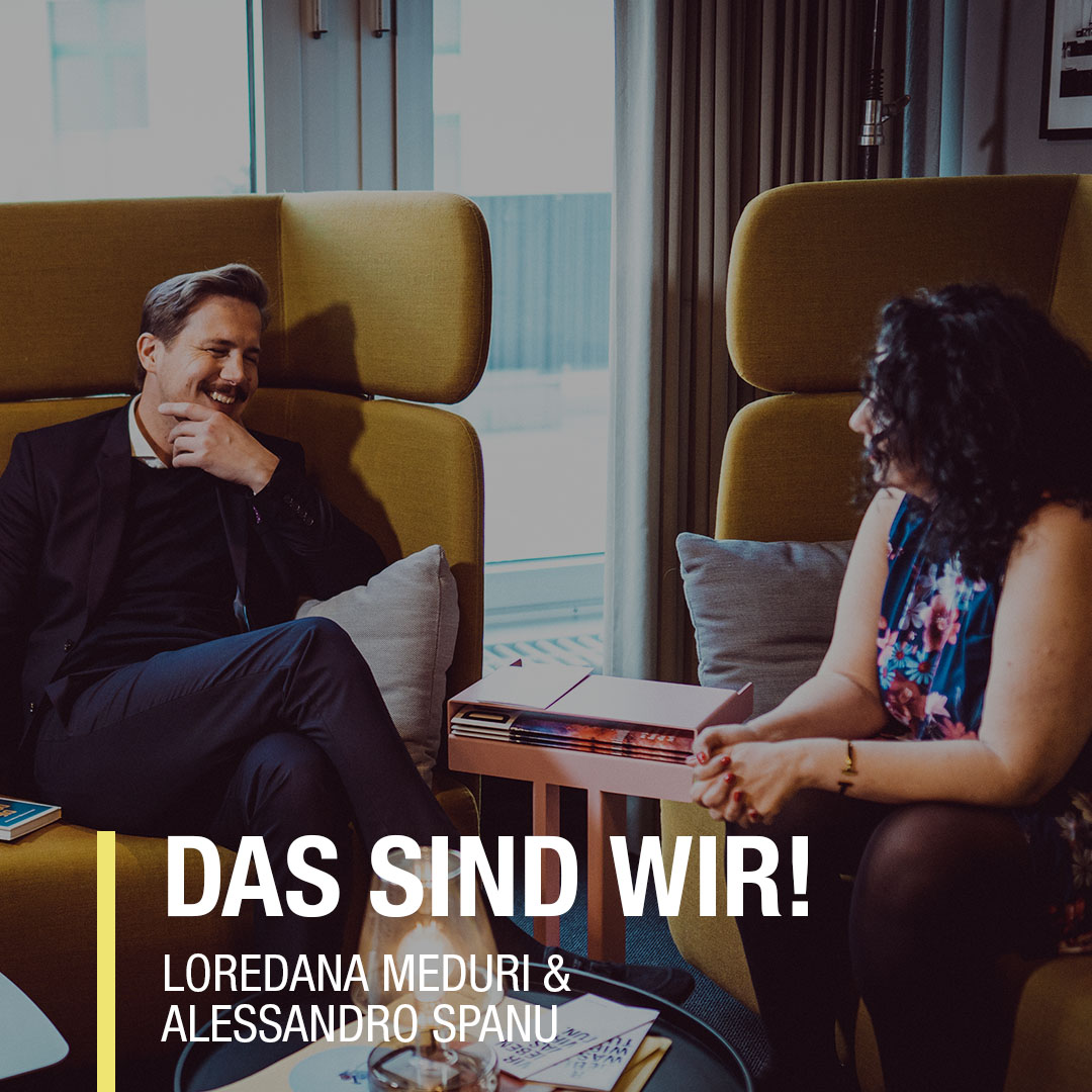 Loredana Meduri und Alessandro Spanu in einem entspannenden Gespräch in einem modernen Raum mit gelben Sessel.
