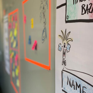 Carnival-themed brainstorming wall featuring colorful sticky notes and a playful character illustration.