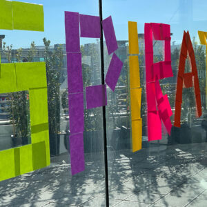 Colorful sticky notes spell out CREATE on a glass window, brightening the workspace with a creative message.