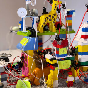 Bunte LEGO-Konstruktion mit Tieren, Geräten und zahlreiche Kabel für ein kreatives Spielumfeld.